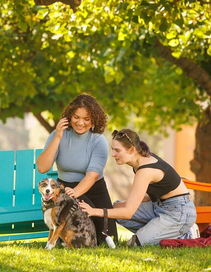 two students pet a dog on the pitzer mounds