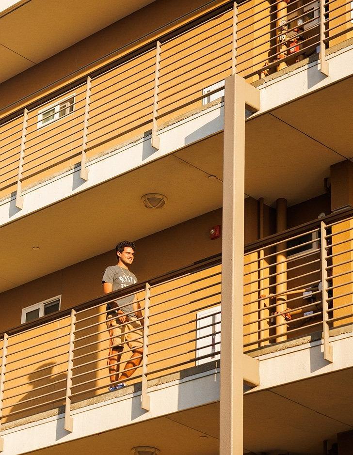 a student stands on the walkway of West Hall